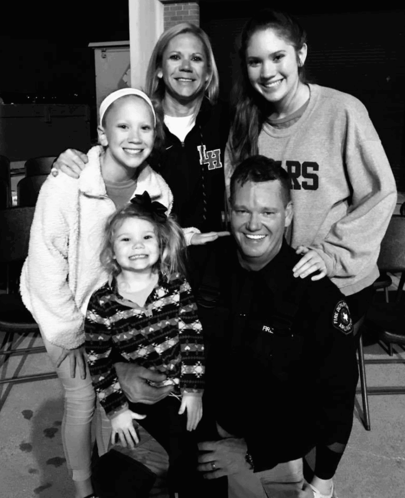 Man in plaid shirt using chainsaw to cut tree branches outdoors.