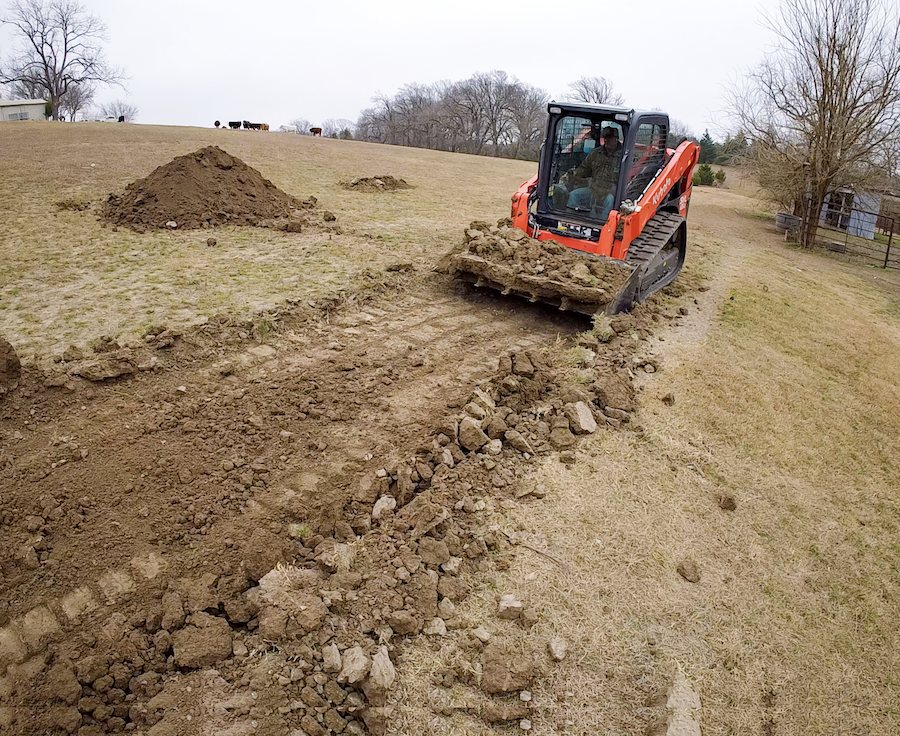 A bulldozer clearing a dirt path in a rural area.