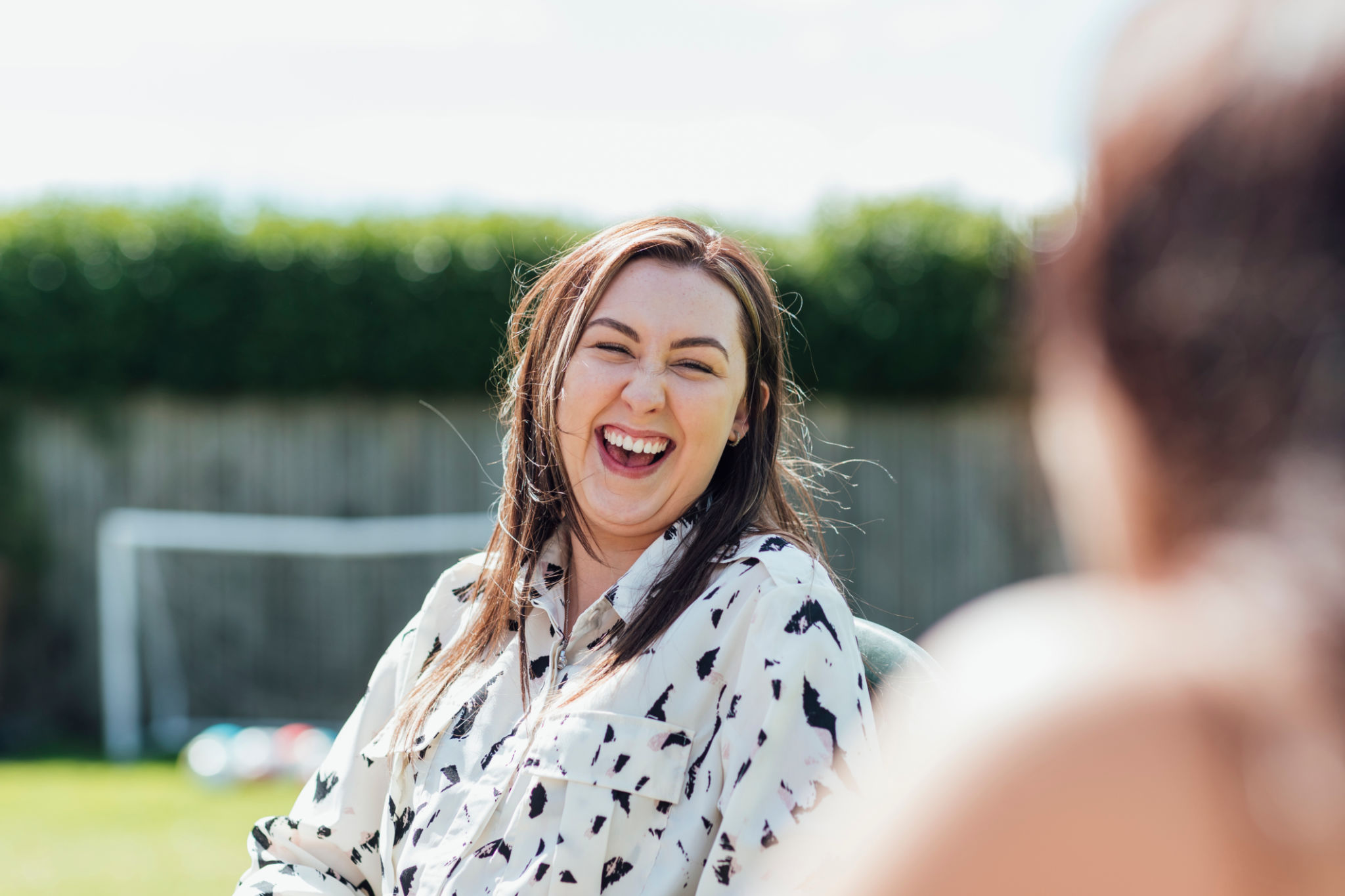Man in plaid shirt using chainsaw to cut tree branches outdoors.